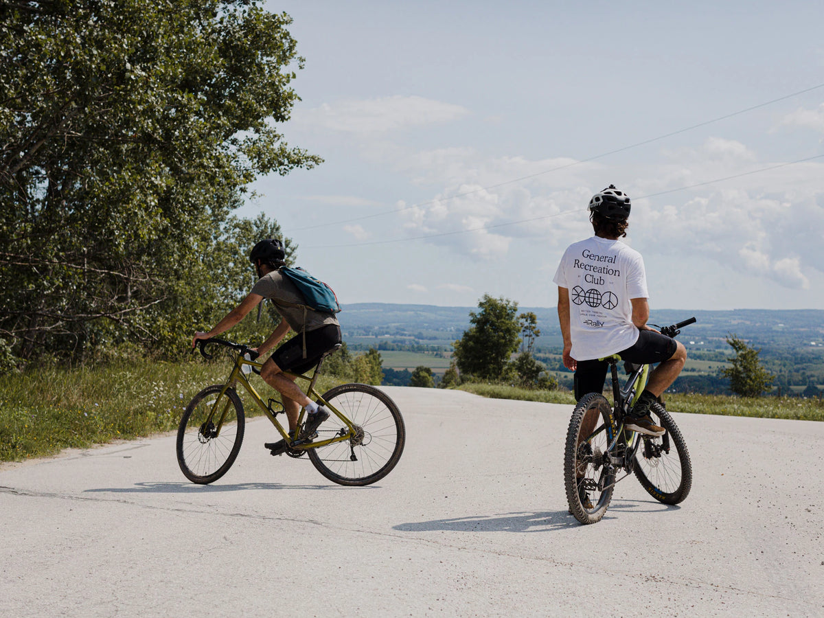 Two men at the top of a mountain bike ride rest
