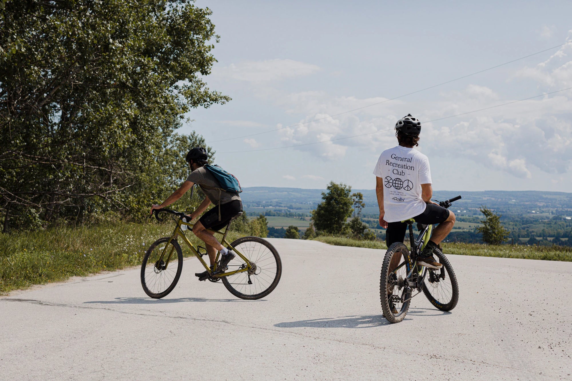 Two men at the top of a mountain bike ride rest